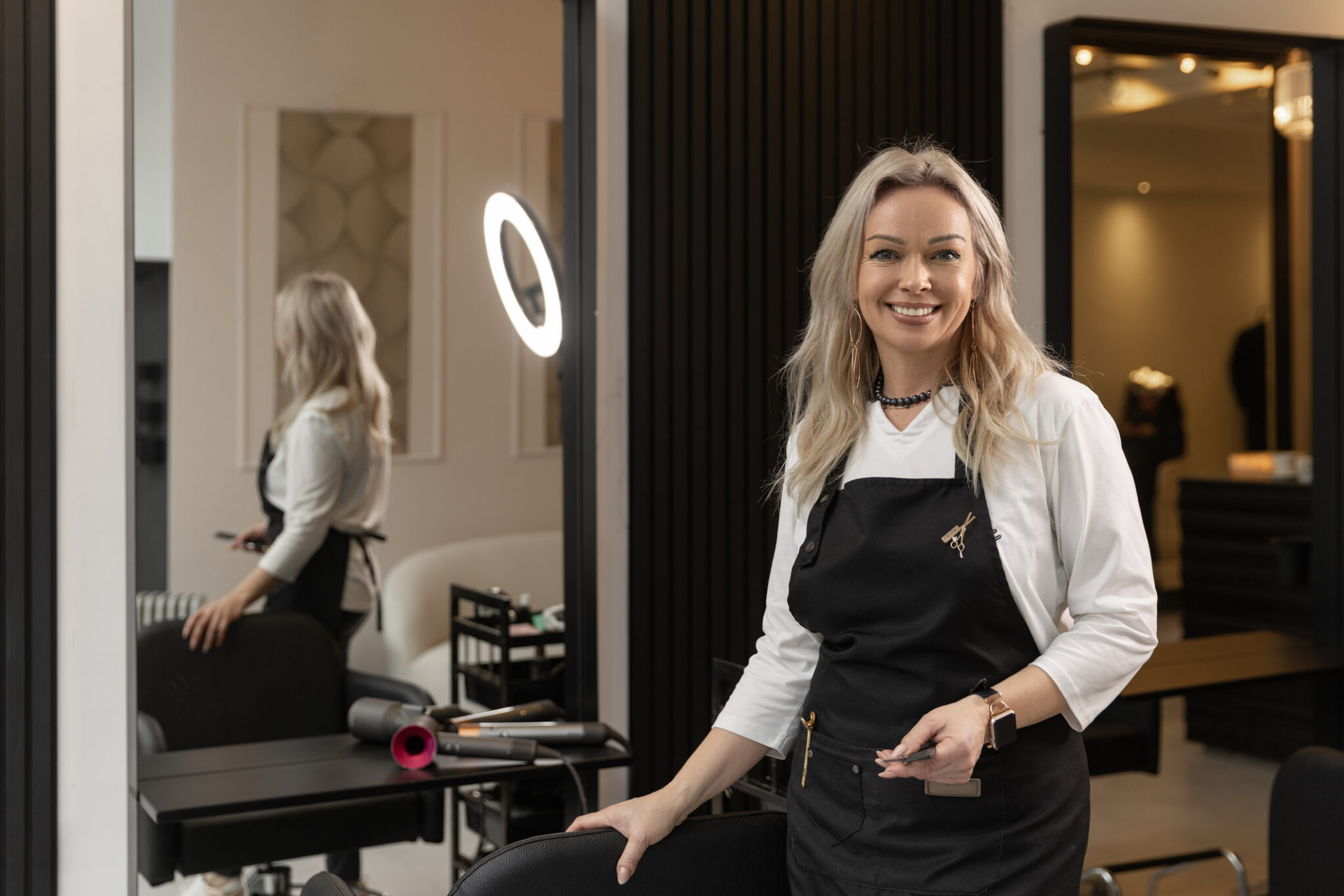 Portrait of a beautiful blonde barber hairdresser at her salon