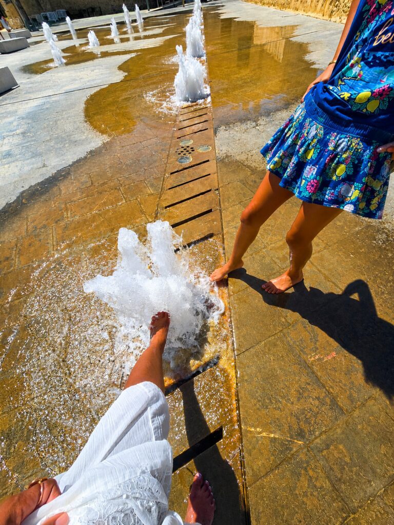 Melanie Martin and her daughter enjoying a splash fountain during their family relocation journey to Alicante, Spain.