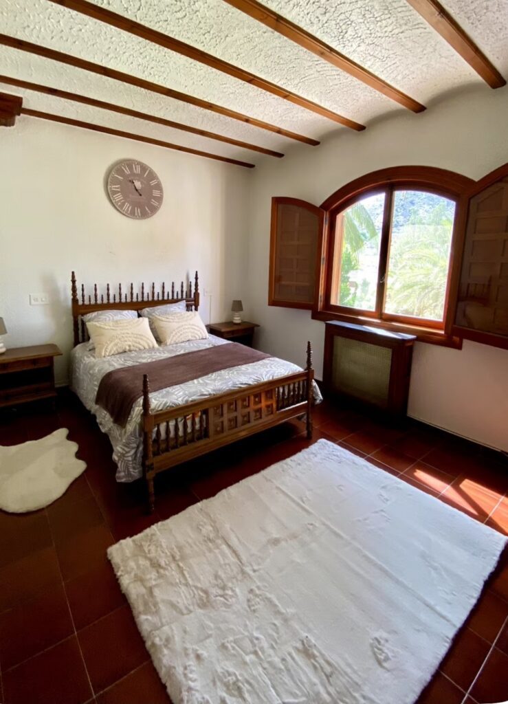 Traditional double bedroom at the Divorce to Domination retreat with ornate wooden bed and arched window