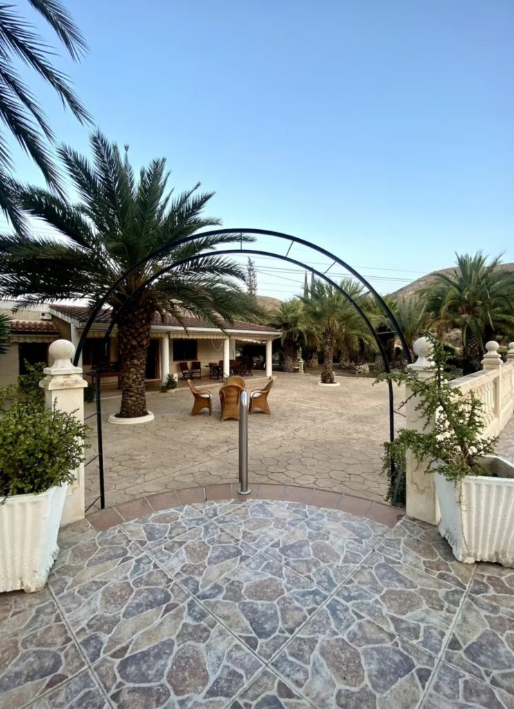 Spanish courtyard at the Divorce to Domination Retreat in Alicante, Spain surrounded by palm trees and mountain views
