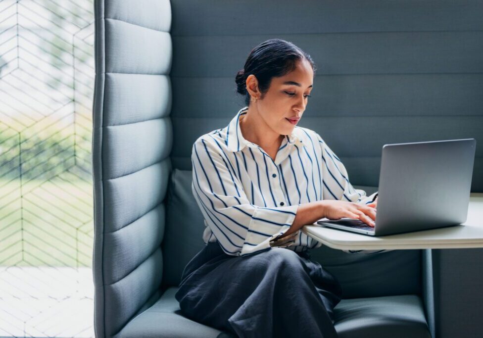 A concentrated woman diligently using a laptop in a private, modern office workspace. Ideal representation of productivity, focused work, and contemporary business environments in today's professional landscape.