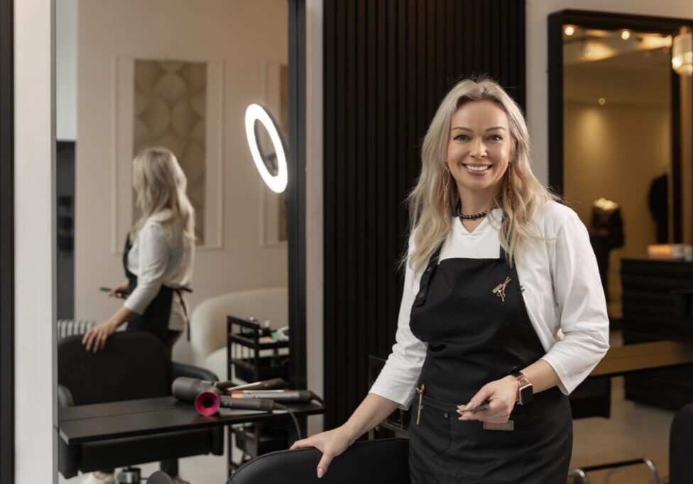 Portrait of a beautiful blonde barber hairdresser at her salon