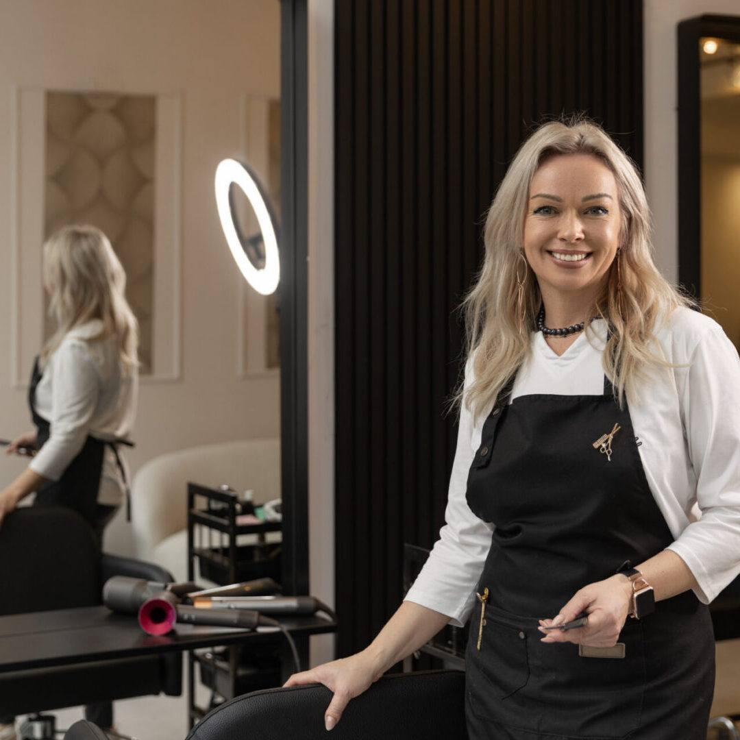 Portrait of a beautiful blonde barber hairdresser at her salon