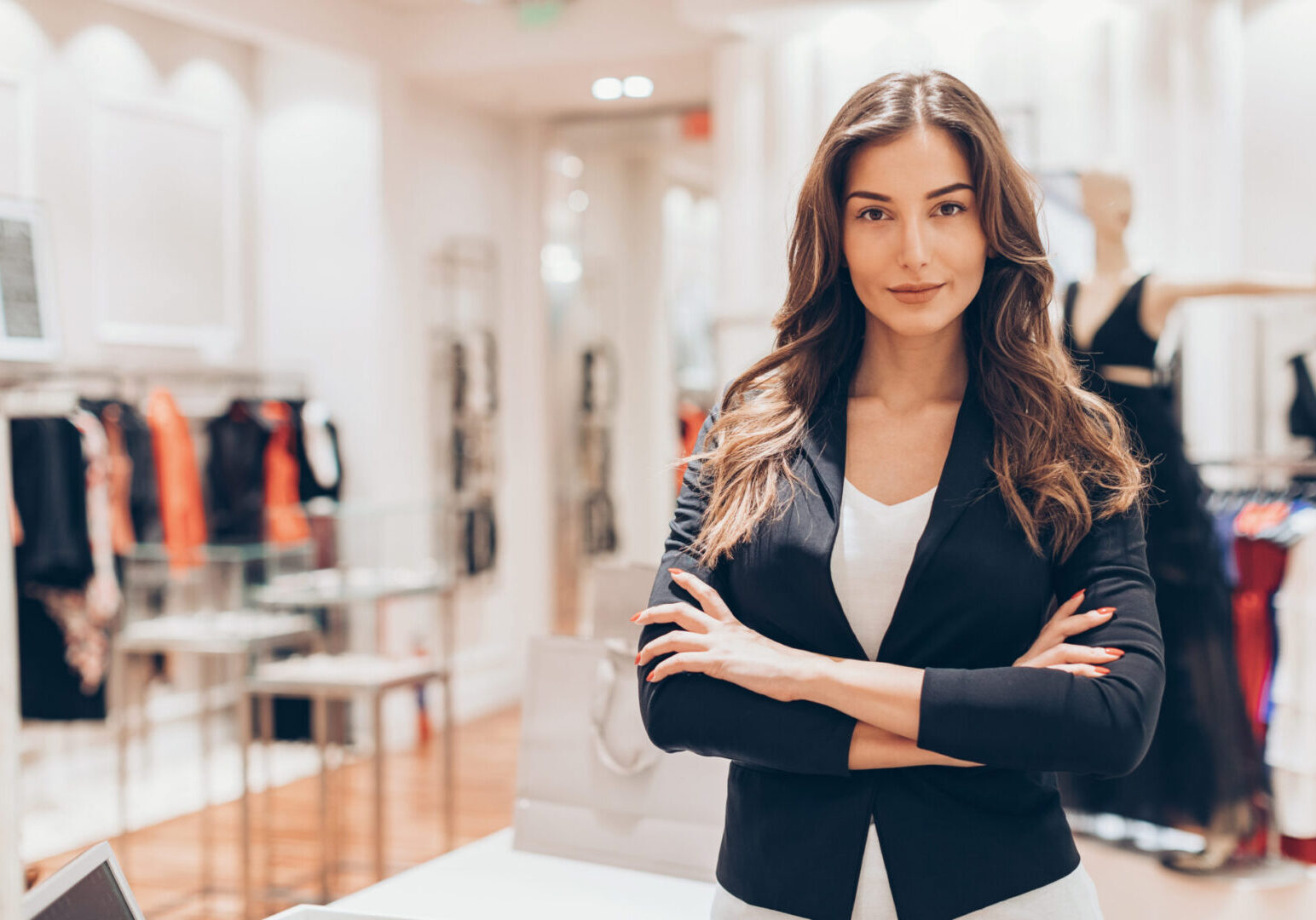 Beautiful woman standing with arms crossed in a fashion store